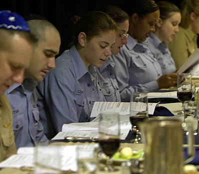 US Navy Crewmembers read from the Passover Hagaddah during the Passover Seder dinner in the wardroom aboard USS Nimitz 